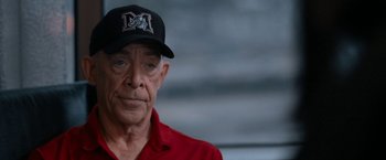 Movie still from “National Champions” (2021), directed by Ric Roman Waugh – An older man wearing a red shirt and a black hat; Close Up shot, Over the shoulder angle