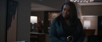 Movie still from “National Champions” (2021), directed by Ric Roman Waugh – A woman sitting in front of a lamp in a living room; Medium shot, Over the shoulder angle