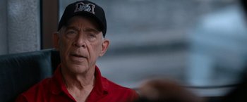 Movie still from “National Champions” (2021), directed by Ric Roman Waugh – An older man wearing a red shirt and a black hat; Close Up shot, Over the shoulder angle