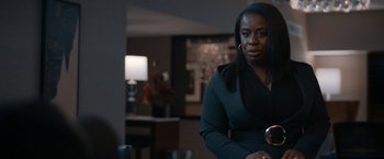 Movie still from “National Champions” (2021), directed by Ric Roman Waugh – A woman sitting in front of a lamp in a room; Medium shot, Over the shoulder angle