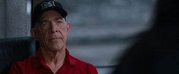Movie still from “National Champions” (2021), directed by Ric Roman Waugh – An older man wearing a red shirt and a baseball cap; Close Up shot, Over the shoulder angle