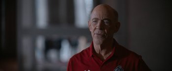 Movie still from “National Champions” (2021), directed by Ric Roman Waugh – An older man in a red shirt is looking at the camera; Close Up shot, Over the shoulder angle