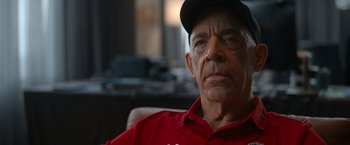 Movie still from “National Champions” (2021), directed by Ric Roman Waugh – An older man wearing a red shirt and a hat; Close Up shot, Over the shoulder angle