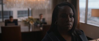 Movie still from “National Champions” (2021), directed by Ric Roman Waugh – A woman in a black shirt is sitting in a room; Close Up shot, Over the shoulder angle