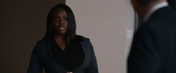 Movie still from “National Champions” (2021), directed by Ric Roman Waugh – A woman in a black dress is standing in a room; Close Up shot, Over the shoulder angle