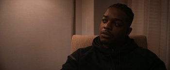 Movie still from “National Champions” (2021), directed by Ric Roman Waugh – A man sitting in a chair in front of a window; Close Up shot, Over the shoulder angle