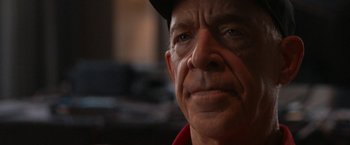 Movie still from “National Champions” (2021), directed by Ric Roman Waugh – An older man wearing a black hat and looking at the camera; Close Up shot, Over the shoulder angle