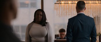 Movie still from “National Champions” (2021), directed by Ric Roman Waugh – A woman standing in front of a man in a suit; Medium shot, Over the shoulder angle