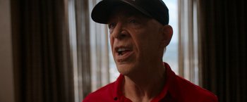 Movie still from “National Champions” (2021), directed by Ric Roman Waugh – An older man wearing a red shirt and a black hat; Close Up shot, Low angle