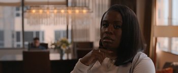 Movie still from “National Champions” (2021), directed by Ric Roman Waugh – A woman that is sitting down in a room; Close Up shot, Over the shoulder angle