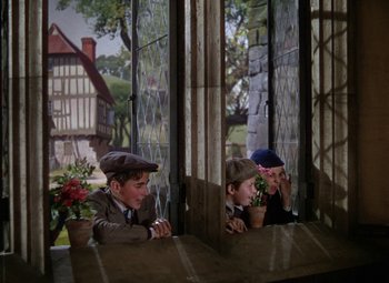 Movie still from “National Velvet” (1944), directed by Clarence Brown – Two young boys sitting at a table in front of stained glass windows; Medium shot, Low angle