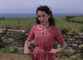 Movie still from “National Velvet” (1944), directed by Clarence Brown – A woman in a red and white dress holding a stick; Medium shot, Low angle