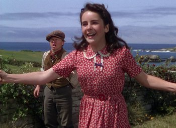 Movie still from “National Velvet” (1944), directed by Clarence Brown – A young woman in a red dress and a man in a brown hat; Medium shot, Low angle