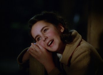 Movie still from “National Velvet” (1944), directed by Clarence Brown – A young girl is smiling while holding her hands to her face; Close Up shot, High angle