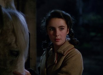Movie still from “National Velvet” (1944), directed by Clarence Brown – A young girl is standing next to a white horse; Close Up shot, Over the shoulder angle