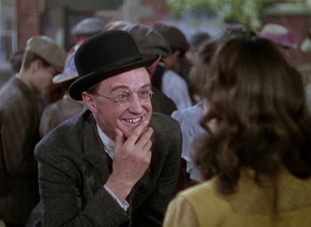 Movie still from “National Velvet” (1944), directed by Clarence Brown – A man wearing a hat and glasses talking to a woman in a crowd; Close Up shot, Over the shoulder angle