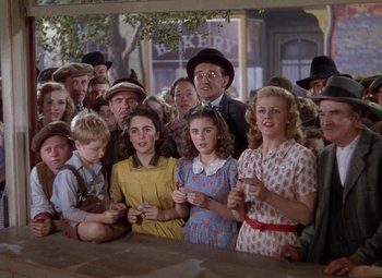 Movie still from “National Velvet” (1944), directed by Clarence Brown – A group of people standing around a table; Medium shot, Low angle