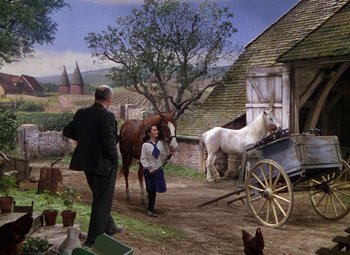 Movie still from “National Velvet” (1944), directed by Clarence Brown – A woman standing next to a horse drawn carriage; Wide shot, High angle