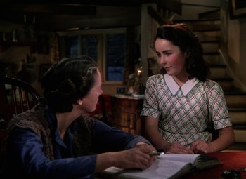 Movie still from “National Velvet” (1944), directed by Clarence Brown – Two people sitting at a table looking at a book; Medium shot, Over the shoulder angle