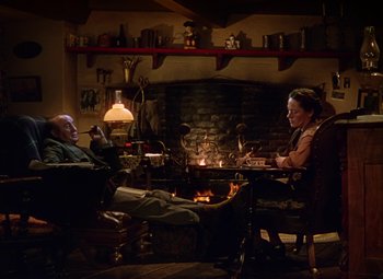 Movie still from “National Velvet” (1944), directed by Clarence Brown – A man and a woman sitting in front of a fireplace; Wide shot, High angle