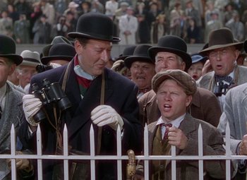 Movie still from “National Velvet” (1944), directed by Clarence Brown – A group of men standing next to each other near a white fence; Medium shot, Low angle
