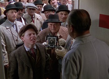 Movie still from “National Velvet” (1944), directed by Clarence Brown – A group of men in suits and hats looking at a camera; Medium shot, High angle