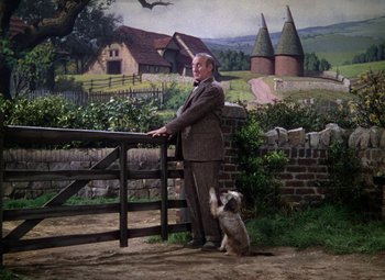 Movie still from “National Velvet” (1944), directed by Clarence Brown – A man and a dog standing next to a fence; Wide shot, Low angle