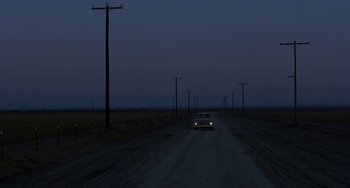 Movie still from “Near Dark” (1987), directed by Kathryn Bigelow – A car driving down a dirt road at night; Extreme Wide shot, High angle
