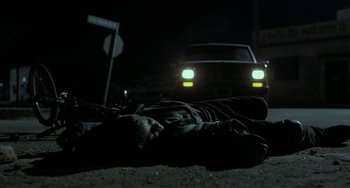 Movie still from “Near Dark” (1987), directed by Kathryn Bigelow – A man laying on the ground in the middle of the night; Wide shot, High angle