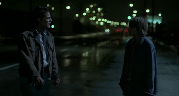 Movie still from “Near Dark” (1987), directed by Kathryn Bigelow – Two people standing in the street at night with lights in the background; Medium shot, Over the shoulder angle