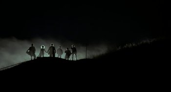 Movie still from “Near Dark” (1987), directed by Kathryn Bigelow – A group of people standing on top of a hill at night; Extreme Wide shot, Low angle