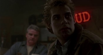 Movie still from “Near Dark” (1987), directed by Kathryn Bigelow – A man in a dark room with another man in the background; Close Up shot, Over the shoulder angle