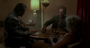 Movie still from “Near Dark” (1987), directed by Kathryn Bigelow – A group of people sitting around a table playing cards; Medium shot, Over the shoulder angle