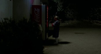Movie still from “Near Dark” (1987), directed by Kathryn Bigelow – A person standing in front of a coke machine at night; Wide shot, High angle