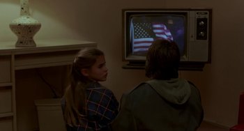 Movie still from “Near Dark” (1987), directed by Kathryn Bigelow – Two people are watching television in a living room; Medium shot, Over the shoulder angle