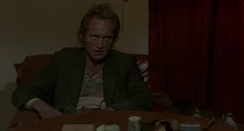 Movie still from “Near Dark” (1987), directed by Kathryn Bigelow – A man sitting at a table in front of a window; Close Up shot, Low angle