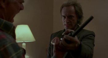 Movie still from “Near Dark” (1987), directed by Kathryn Bigelow – A man holding a knife in a room; Close Up shot, Low angle
