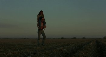 Movie still from “Near Dark” (1987), directed by Kathryn Bigelow – A man carrying a woman on his back in the middle of a field; Wide shot, Low angle