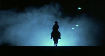 Movie still from “Near Dark” (1987), directed by Kathryn Bigelow – A person riding a horse in a dark area; Wide shot, Low angle