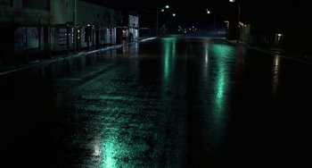 Movie still from “Near Dark” (1987), directed by Kathryn Bigelow – A wet street at night lit by street lights; Extreme Wide shot, High angle