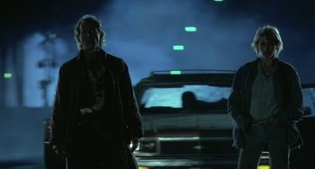 Movie still from “Near Dark” (1987), directed by Kathryn Bigelow – A man and a woman standing in front of a car at night; Medium shot, Low angle