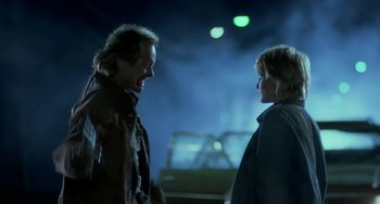 Movie still from “Near Dark” (1987), directed by Kathryn Bigelow – Two people talking to each other in a parking lot at night; Medium shot, Over the shoulder angle
