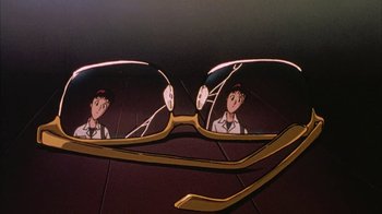Movie still from “Neon Genesis Evangelion: Death & Rebirth” (1997), directed by Tensai Okamura – A pair of glasses with a man and a woman reflected in it; Extreme Close Up shot, Low angle