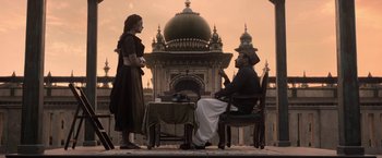 Movie still from “Gangubai Kathiawadi” (2022), directed by Sanjay Leela Bhansali – A man and a woman sitting at a table outside; Wide shot, Low angle