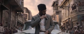Movie still from “Gangubai Kathiawadi” (2022), directed by Sanjay Leela Bhansali – A man in a suit and a hat standing in front of a car; Medium shot, Low angle