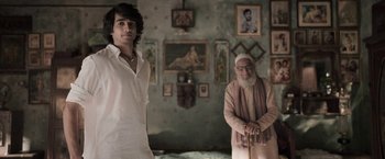 Movie still from “Gangubai Kathiawadi” (2022), directed by Sanjay Leela Bhansali – A man standing next to an older man in a room; Medium shot, Over the shoulder angle