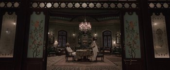 Movie still from “Gangubai Kathiawadi” (2022), directed by Sanjay Leela Bhansali – Two people are sitting at a table in a room; Wide shot, Low angle