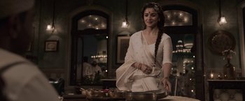 Movie still from “Gangubai Kathiawadi” (2022), directed by Sanjay Leela Bhansali – A woman standing in front of a bowl of food; Medium shot, Over the shoulder angle