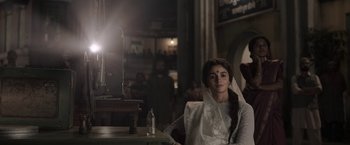 Movie still from “Gangubai Kathiawadi” (2022), directed by Sanjay Leela Bhansali – A woman sitting in front of a candle light; Medium shot, Low angle