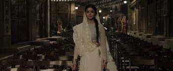 Movie still from “Gangubai Kathiawadi” (2022), directed by Sanjay Leela Bhansali – A woman in a white dress standing in a room full of chairs; Medium shot, Low angle